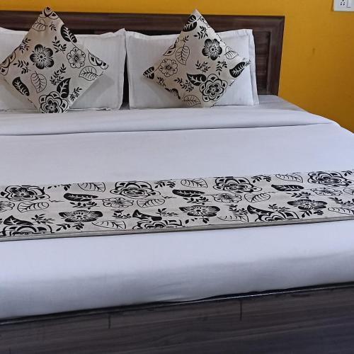 a bed with a black and white blanket and pillows at Hotel Suraj in Rishīkesh