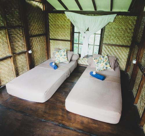- deux canapés blancs dans une chambre avec fenêtres dans l'établissement Bale Jukung, à Tanjung