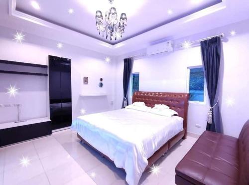 een slaapkamer met een bed, een bank en een kroonluchter bij Sun Poolvilla Bangsaray in Bang Sare