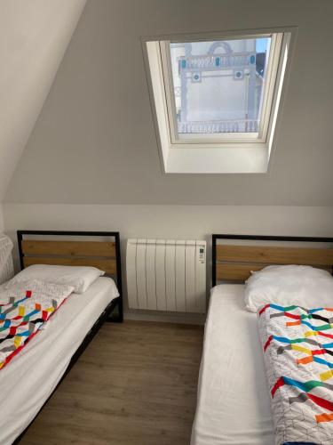 two beds in a room with a window at Napoléon in Wimereux