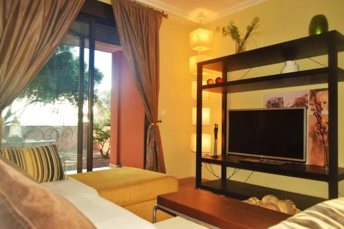 een woonkamer met een flatscreen-tv en een bank bij Paraiso La Tejita, preciosa terraza y playa in La Tejita