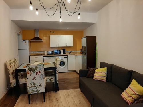 een woonkamer met een bank en een tafel en een keuken bij Apartamentos Andrada in Casar de Cáceres