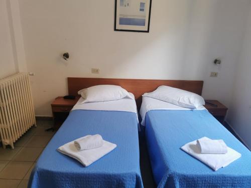 2 camas en una habitación con sábanas azules y toallas blancas en locanda foresteria, en Milán
