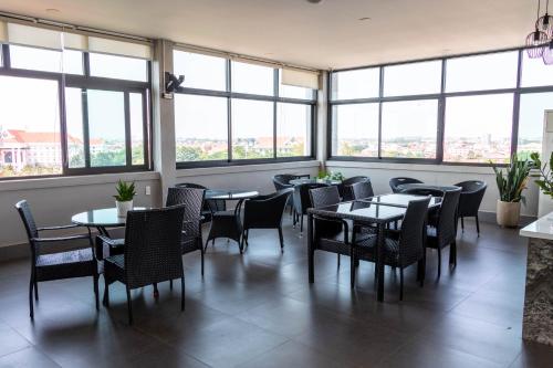 a restaurant with tables and chairs and large windows at Urbanite Hotel in Vientiane