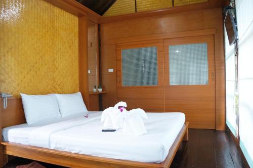a bed with white sheets and a doll on it at Chanpraya Resort in Chanthaburi