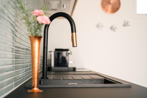 a kitchen sink with a vase of pink flowers next to it at Sublime Nooks in Havelock North