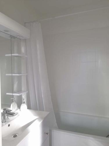une salle de bain blanche avec un lavabo et un miroir dans l'établissement Studio proche du centre ville et de la plage, à Villers-sur-Mer