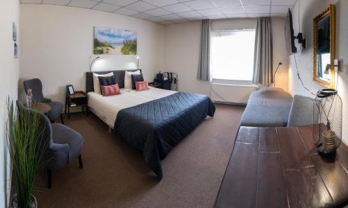ein Hotelzimmer mit einem Bett, einem Tisch und Stühlen in der Unterkunft Hotel de Zwaan in Schoondijke