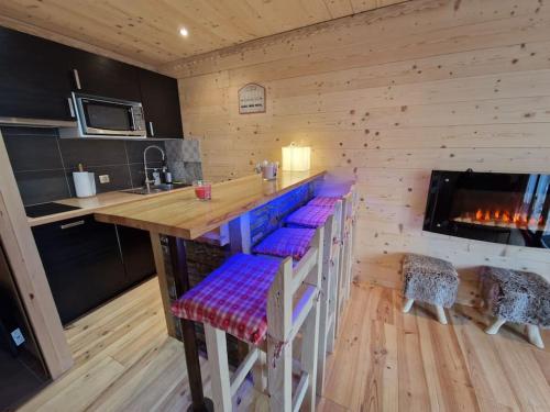 una cocina con barra en una cabaña de madera en Charmant T2 rénové- Praloup 1600-parking privé, proche station en Uvernet-Fours