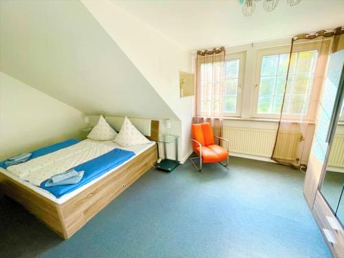 ein Schlafzimmer mit einem Bett und einem orangenen Stuhl in der Unterkunft Villa Ferienhaus EMG für Familien und Gruppen in Celle Hannover in Celle