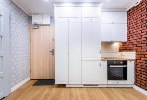 a kitchen with white cabinets and a brick wall at Cztery Oceany 209 in Gdańsk