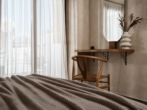 a bedroom with a bed and a mirror and a chair at GARDELLI RESORT in Laganas