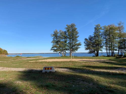 una señal en medio de un campo cerca del agua en Videvägen 3 en Sölvesborg