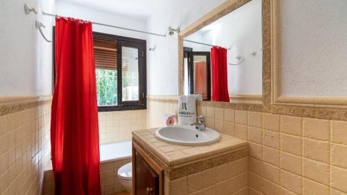 ein Badezimmer mit einem Waschbecken und einem roten Duschvorhang in der Unterkunft Casa Puente Palo Igualeja by Ruralidays in Igualeja
