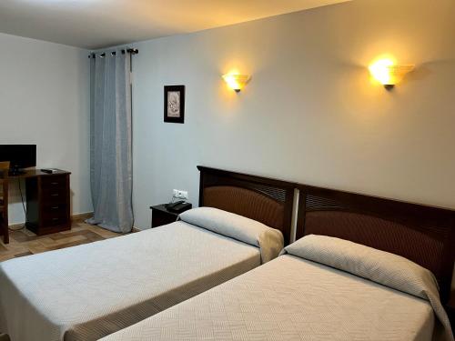 a bedroom with two beds and two lights on the wall at Hotel Cervantes in Zafra