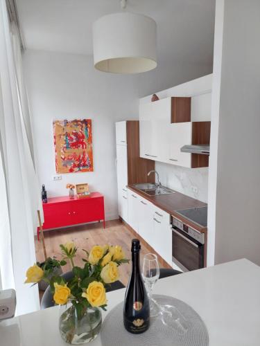 eine weiße Küche mit einem Tisch und einer Flasche Wein in der Unterkunft Vienna Charm Apartment in Wien