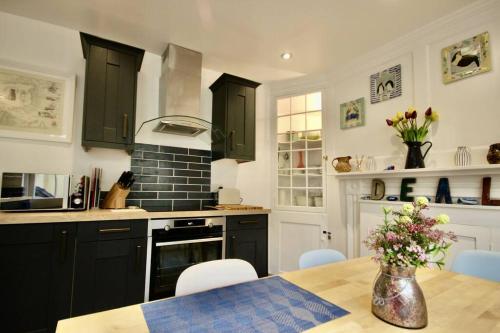 een keuken met zwarte kasten en een tafel met bloemen bij Dexter's House in Kent