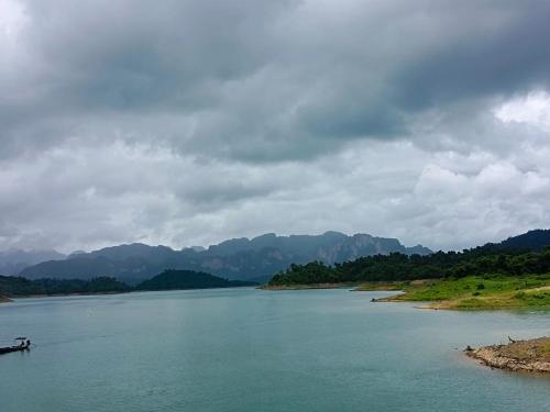a river with a boat in it on a cloudy day at Khao Sok River & Jungle Bungalow in Khao Sok