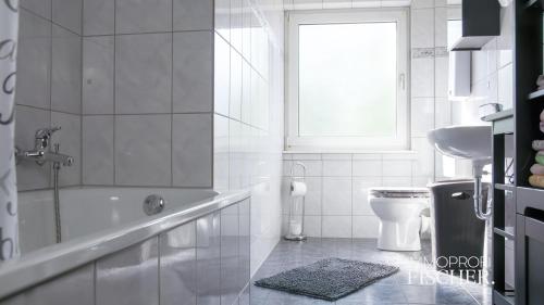 een badkamer met een bad, een toilet en een raam bij Doppelzimmer im Zentrum von Moers in Moers