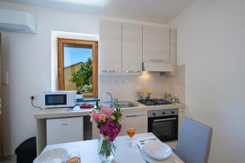 a kitchen with a table with a vase of flowers on it at Grazie papà - The beginning of the path of the gods in Pianillo