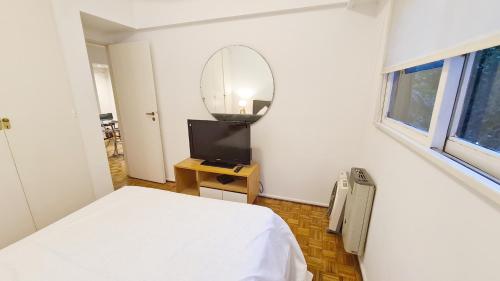 ein Schlafzimmer mit einem weißen Bett und einem Spiegel in der Unterkunft Alquiler temporario en Vicente López in Vicente López