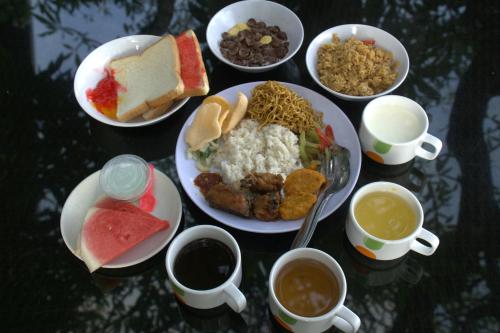 a table with plates of food and cups of coffee at Singaraja Hotel - CHSE Certified in Singaraja