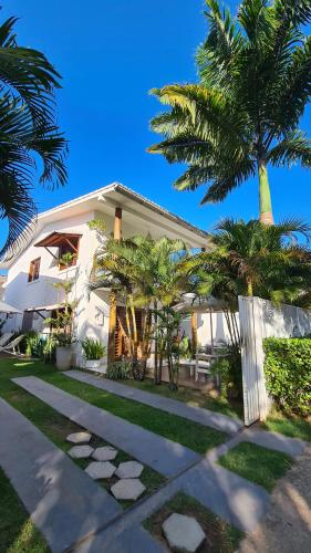 una casa blanca con palmeras delante en Vivenda Dias, en Pipa