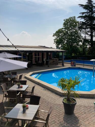 a swimming pool with tables and chairs next to a building at Family Woodlodge High Chaparral in Oorsbeek
