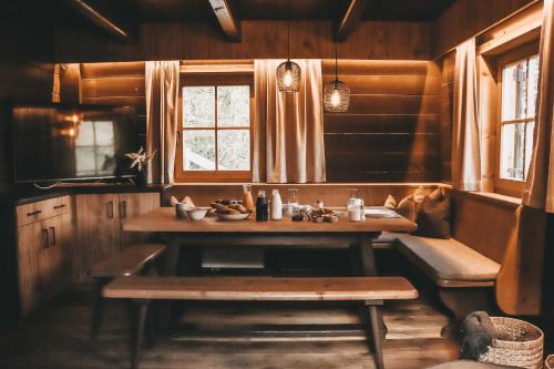 eine Küche mit einem Tisch, einer Bank und Fenstern in der Unterkunft Hüttendorf Schlögelberger in Sankt Margarethen im Lungau