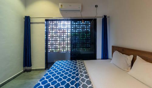 a bedroom with a bed and a window with blue curtains at Two Villa by StayVista with Infinity Pool, Farm & Mountain Views, Modern Interiors in Karjat