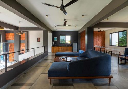 a living room with a blue couch and a table at Two Villa by StayVista with Infinity Pool, Farm & Mountain Views, Modern Interiors in Karjat