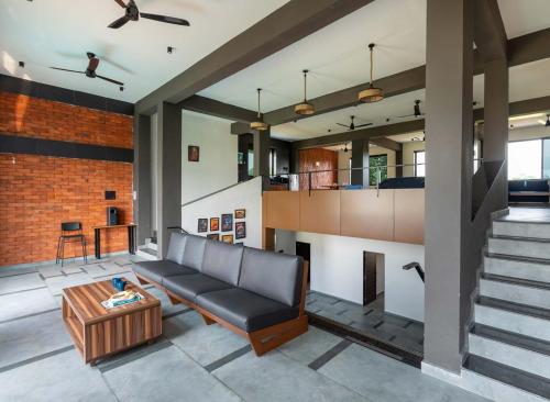 a living room with a couch and a staircase at Two Villa by StayVista with Infinity Pool, Farm & Mountain Views, Modern Interiors in Karjat