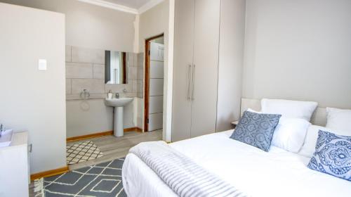 a bedroom with a bed and a bathroom with a sink at 10 Tula in Welkom