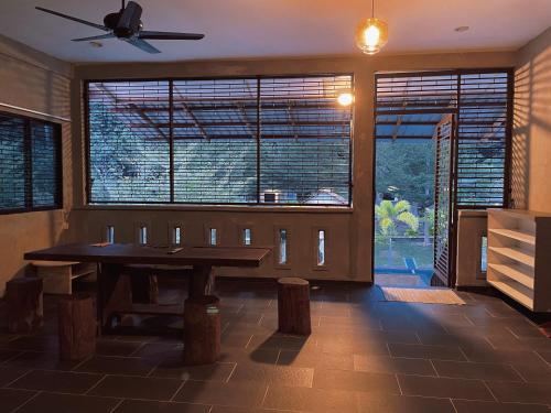 a dining room with a table and large windows at Pangkor Nature View House in Pangkor