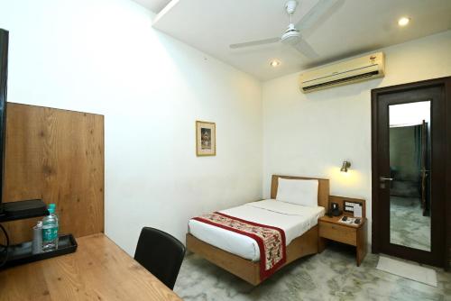 a bedroom with a bed and a table and a mirror at Hotel Yulia in Jaipur