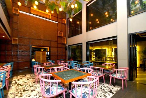 a restaurant with pink and blue tables and chairs at Hotel Yulia in Jaipur