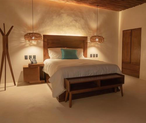 a bedroom with a bed and a table and two lights at Puerta del Cielo Hotel Origen in Bacalar