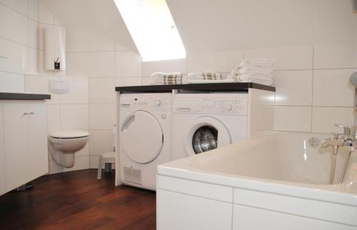 La salle de bains blanche est pourvue d'un lave-linge et de toilettes. dans l'établissement Freesenpark Freesenpark, à Norderney