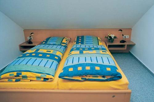 1 dormitorio con 3 camas con almohadas azules y amarillas en Dünenwind Dünenwind 01 en Norderney