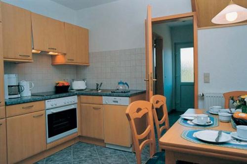 a kitchen with wooden cabinets and a table and chairs at Dünenwind Dünenwind 02 in Norderney