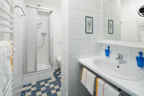 La salle de bains blanche est pourvue d'un lavabo et d'une douche. dans l'établissement Metropol Metropol 22, à Norderney