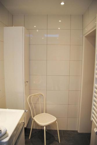une chaise dans une salle de bains avec un mur blanc dans l'établissement Metropol Metropol 23, à Norderney