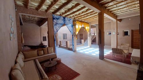 una sala de estar con sofá y una habitación con mesa en Dar Bilal, en Aït Ben Haddou