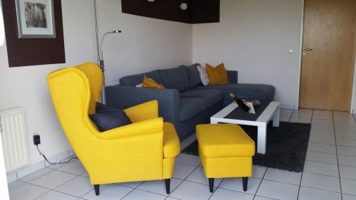 ein Wohnzimmer mit zwei gelben Stühlen und einem Sofa in der Unterkunft Residenz am Deich NDD 12 in Norden