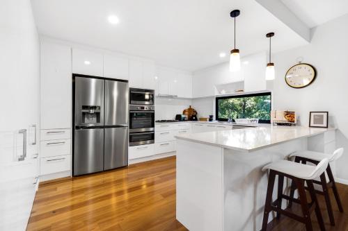 a white kitchen with stainless steel appliances and wooden floors at Forest Haven 2 BR Styled Modern Sanctuary at Maleny in Maleny