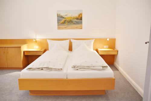 a bedroom with a large white bed with two pillows at Ferienhaus Pauls Ferienhaus Pauls, Whg 03 in Norderney