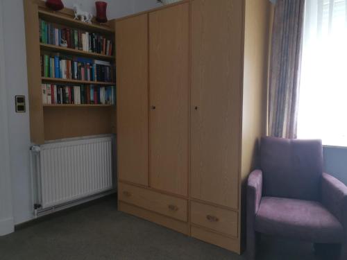 1 dormitorio con estante de libros y silla en Haus Mindermann Mindermann 03, en Norderney
