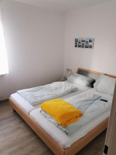 een slaapkamer met een bed met een geel kussen erop bij Haus Sieben Wohnung 1 Roonstraße 3 in Norderney