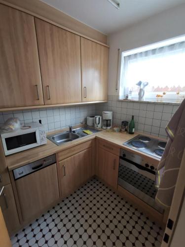 een keuken met houten kasten, een wastafel en een magnetron bij Haus Sieben Wohnung 1 Roonstraße 3 in Norderney