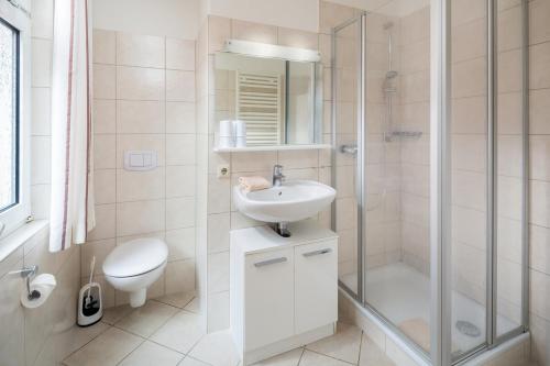 een badkamer met een douche, een wastafel en een toilet bij Lüttje Huus Lüttje Huus 02 in Norderney